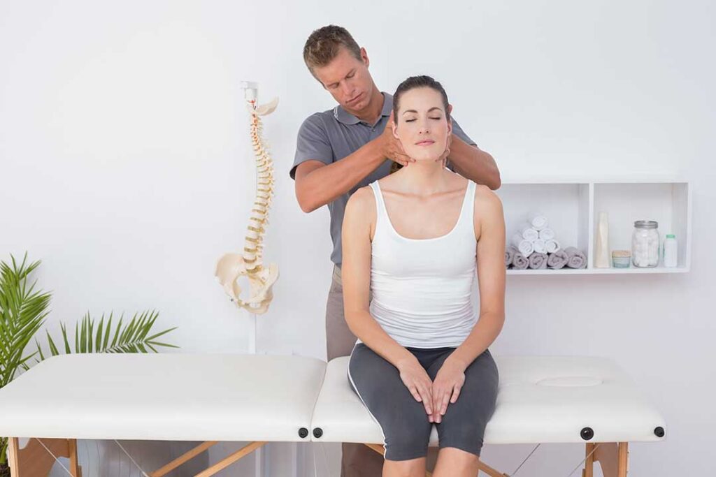 Person examining a painful foot while standing beside a simple spine and leg alignment diagram.