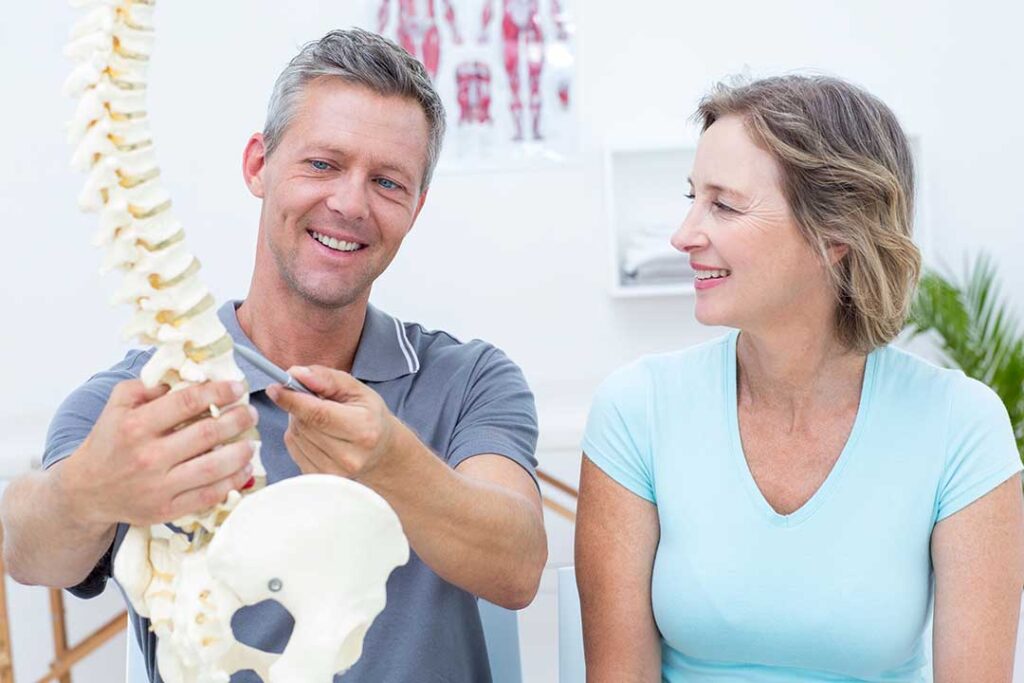 Adult receiving a chiropractic adjustment while reviewing posture and mobility exercises with a practitioner.
