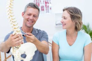 Adult receiving a chiropractic adjustment while reviewing posture and mobility exercises with a practitioner.